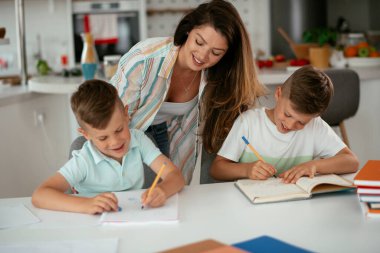 Anne oğullarıyla ödev yapıyor.