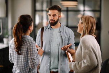 Modern açık uzay ofisinde sıradan iş adamlarından oluşan bir grup. İş kadınları ve işadamları yeni proje hakkında konuşuyor.