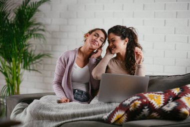 Kız arkadaşlar evde dizüstü bilgisayardan müzik dinlerler. Kızlar apartmanda eğleniyor..