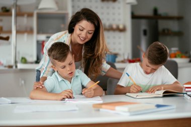 Anne oğullarıyla ödev yapıyor.