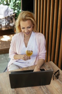 Takım elbiseli, şarap içen ve dizüstü bilgisayarla çalışan güzel bir iş kadını. İş kadını restoranda eğleniyor.