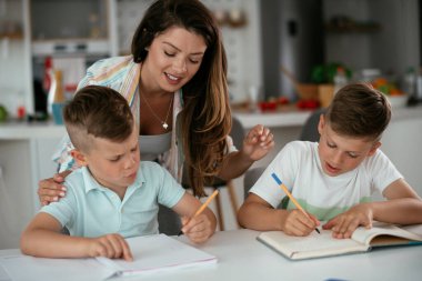 Anne oğullarıyla ödev yapıyor.