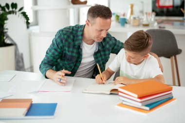 Baba, oğluna ev ödevinde yardım ediyor. Küçük çocuk evde öğreniyor..