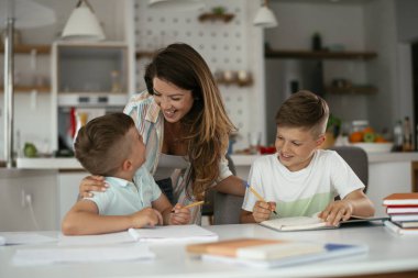 Anne oğullarıyla ödev yapıyor.