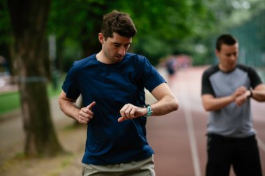Gençler yarış pistinde antrenman yapıyor. İki genç arkadaş atletizm pistinde koşuyor.