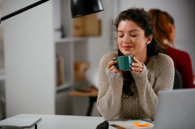 Genç ve güzel bir kadın ofis masasında oturuyor.