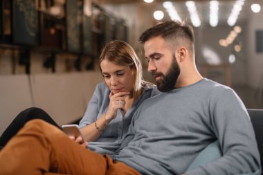 Ofiste oturan ve cep telefonuna bakan ortaklar. Meslektaşlar yeni mobil uygulama hakkında tartışıyor.