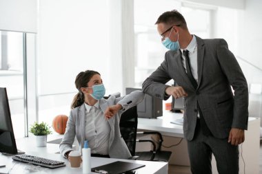 Ofiste tıbbi maskeli bir iş adamı ve iş kadını var. Covid-19 saatinde selamlar..