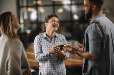 Modern açık uzay ofisinde sıradan iş adamlarından oluşan bir grup. İş kadınları ve işadamları yeni proje hakkında konuşuyor.