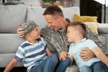 Üniformalı baba, oğullarıyla kanepede vakit geçiriyor. 