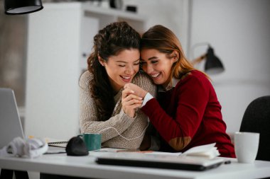 Açık uzay ofisinde konuşan ve gülen mutlu iş kadınları