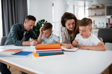 Ebeveynler çocuklara ev ödevlerinde yardım ediyorlar. Küçük çocuklar evde öğreniyor..
