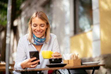 Kafede mesajlaşan genç kadın.