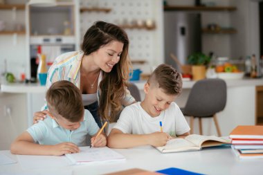 Anne oğullarıyla ödev yapıyor.