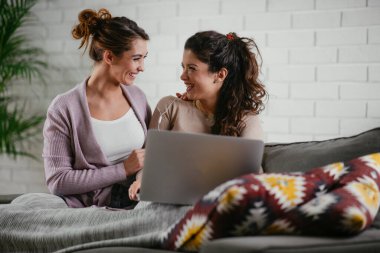Kız arkadaşlar evde dizüstü bilgisayardan müzik dinlerler. Kızlar apartmanda eğleniyor..