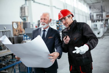 İş arkadaşları birlikte çalışıyor. Fabrikada mimar ve işçi..