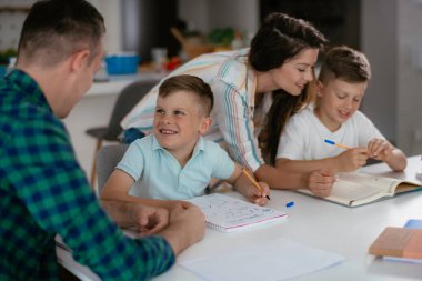 Anne ve baba oğullarına ev ödevlerinde yardım ederler.