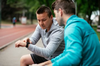 Koşmaktan istirahat eden zinde genç adamlar. Dışarıda antrenman yapan iki arkadaş..