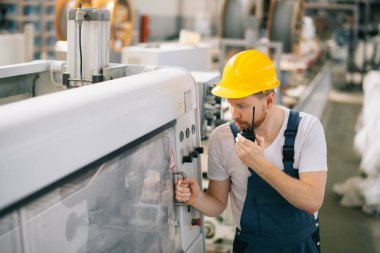Üretim hattındaki fabrika işçisi. Fabrikada çalışan kasklı bir adam..