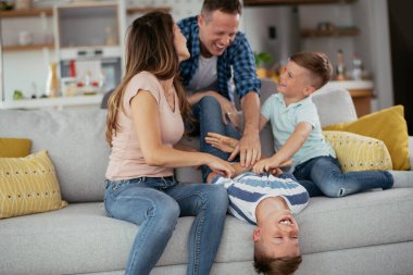 Genç bir aile evde eğleniyor. Mutlu ebeveynler ve çocuklar eğleniyor..