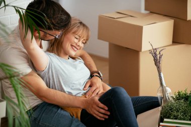 Evde kutuların yanında kucaklaşan çift.