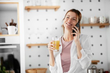 Mutfaktaki kadın. Mutfakta telefon kullanan güzel bir kadın..