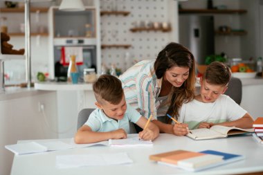 Anne oğullarıyla ödev yapıyor.