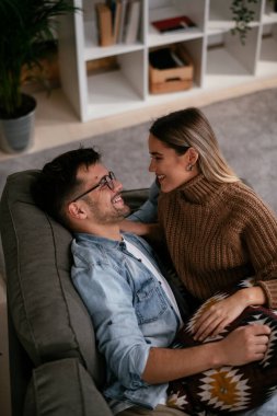 Genç adam ve kız arkadaşı oturma odasında kanepede.