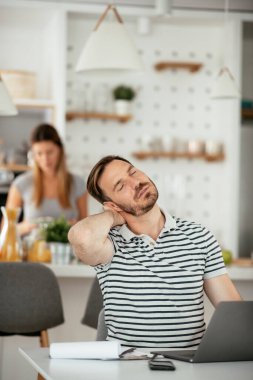 Adam masada çalışıyor, kadın mutfakta.