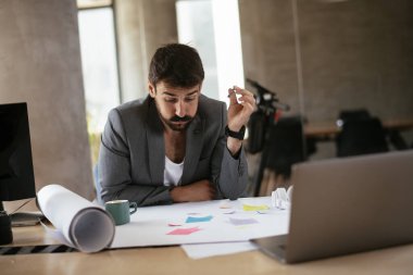 Yorgun iş adamı proje üzerinde çalışıyor. Ofiste çalışan genç bir işadamı..