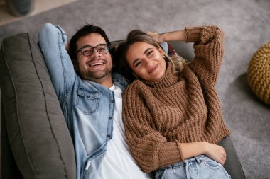 Genç adam ve kız arkadaşı oturma odasında kanepede.