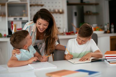 Anne oğullarıyla ödev yapıyor.