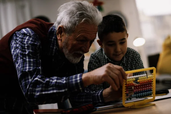 Büyükbaba ve torun birlikte ev ödevi yapıyorlar. Büyükbaba ve torun evde eğleniyor..