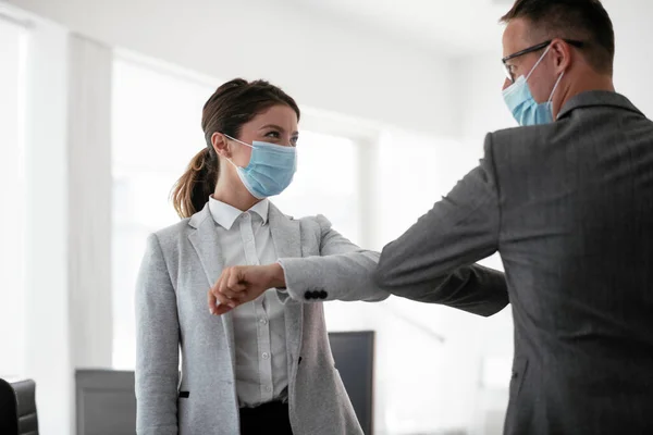 Businessman and businesswoman with medical mask in office. Greetings in Covid-19 time.