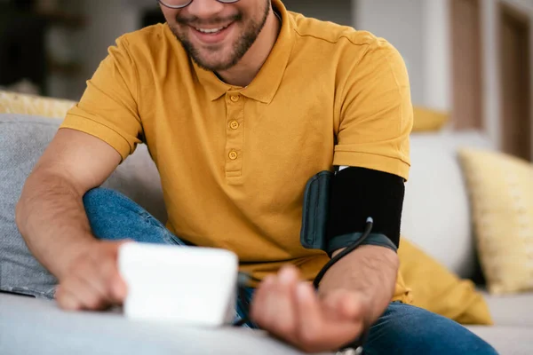 Evdeki kanepede kan basıncını ölçen bir adam..