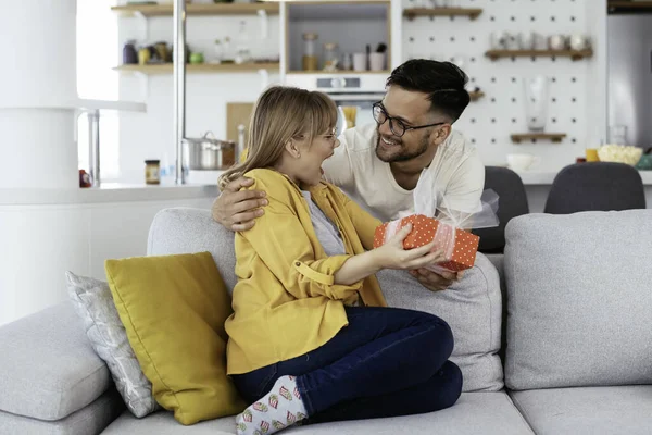 Man surprising his girlfriend with a gift. Young man giving gift box to his girlfriend.