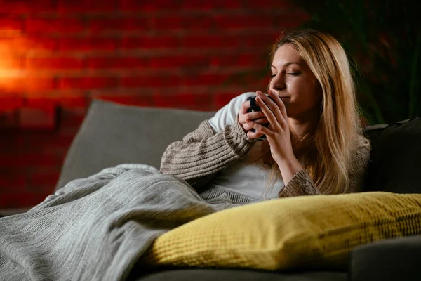 Mulher Loira Bonita Deitada Sofá Assistindo Bebendo Chá Quente — Fotografia de Stock