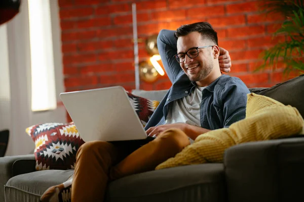 Χαμογελαστός Νεαρός Άνδρας Φορώντας Γυαλιά Laptop Στο Σαλόνι — Φωτογραφία Αρχείου