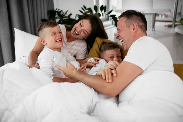 Молодая Семья Наслаждается Постели Счастливые Родители Сыновьями Отдыхающими Постели — стоковое фото