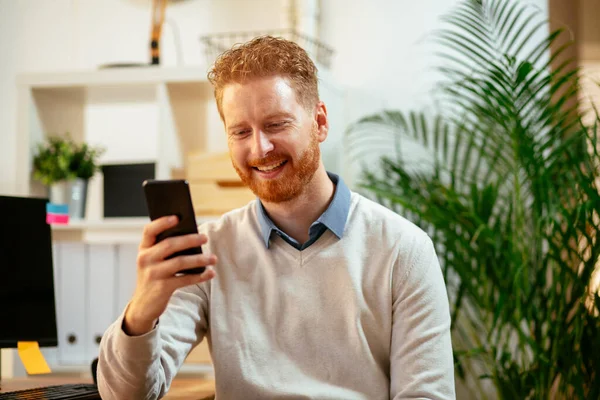 handsome businessman with ginger hair using smartphone in the office