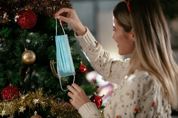 Junge Frau Schmückt Weihnachtsbaum Hause Mit Medizinischer Gesichtsmaske Weihnachtsferien Während — Stockfoto