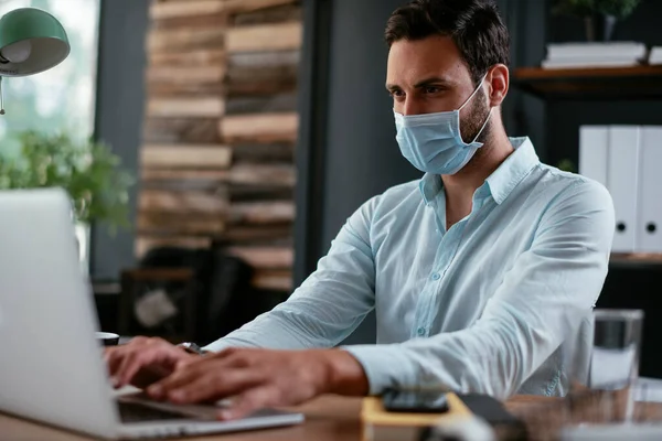 Businessmen with medical mask working in office. Businessman at his work place with medical mask. Covid-19 concept.