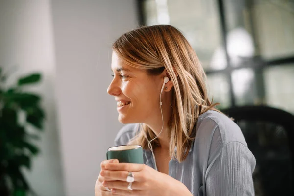 커피를 마시는 아름다운 여자는 아침에 사무실 책상에서 커피를 즐긴다 스톡 이미지