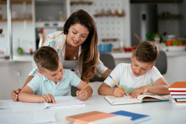 Anne oğullarıyla ödev yapıyor.