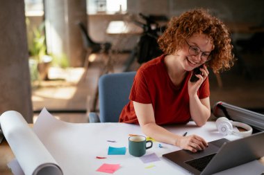 Projeler üzerinde çalışan güzel bir iş kadını. Genç iş kadını telefonda konuşuyor..