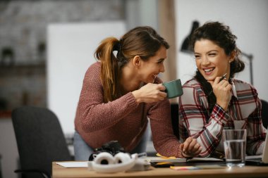 Açık uzay ofisinde konuşan ve gülen mutlu iş kadınları