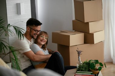 Evde kutuların yanında kucaklaşan çift.