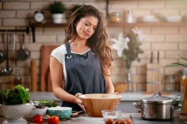 Gülümseyen kadın mutfakta yemek yapıyor.