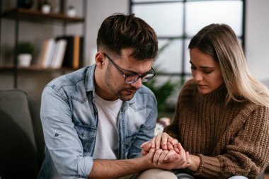 Genç adam ve kız arkadaşı oturma odasında kanepede.