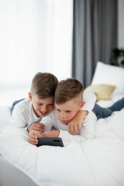 İki küçük kardeş telefonda oyun oynuyorlar. Güzel çocuklar evde eğleniyor..